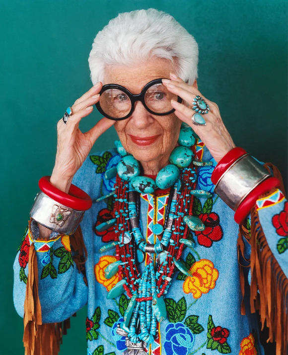 Iris Apfel mit großer schwarzer Brille und auffälligem Schmuck