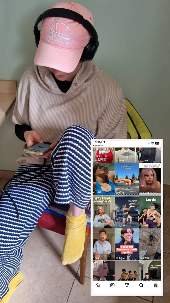 Iris sitzt mit Kopfhörern und schaut auf ihr Smartphone